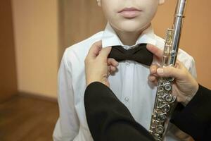 un música profesor prepara su estudiante para un musical actuación. él endereza su arco atar. foto