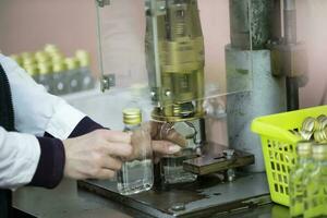 Worker hands and empty bottles on a conveyor belt in the production of alcoholic beverages. photo