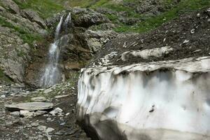 Waterfall in the mountains against the backdrop of a descended glacier. photo