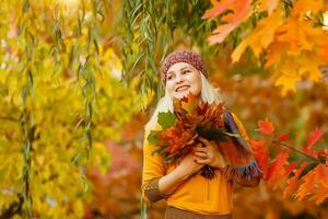 retrato de alegre joven mujer con otoño hojas en frente de follaje haciendo selfie foto