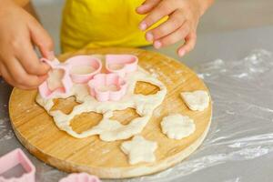 little girl makes cookies from the dough in the kitchen at home photo