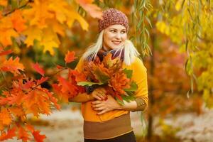 joven mujer con otoño hojas en mano y otoño amarillo arce jardín antecedentes foto