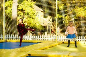 Happy school girl jumping on trampoline in the autumn park photo