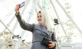 The young girl walks around the city near sights. Ferris wheel. Amusement park. autumn photo