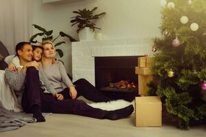 Happy family father mother and children sitting by fireplace on Christmas Eve photo