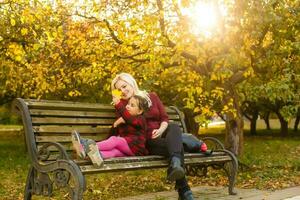 mother and daughter on a bench in autumn park photo