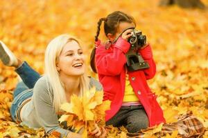 linda familia caminando en un otoño parque. madre con pequeño hija foto