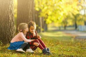 dos pequeño muchachas en otoño parque foto