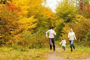 Picture of lovely family in autumn park, young parents with nice adorable daughter playing outdoors, have fun on backyard in fall, happy family enjoy autumnal nature photo