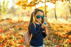 little girl with hourglass surrounded by autumn foliage photo