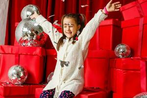 Cheerful cute little child girl with present. Little girl is among the Christmas gifts. photo