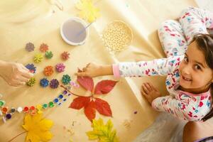 little girl is painting the color on pine cones photo