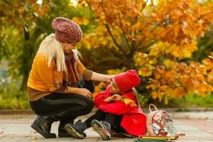 Mom leads her daughter to school. Return to school. Woman and girl with backpack behind the back. Beginning of lessons. First day of fall. photo