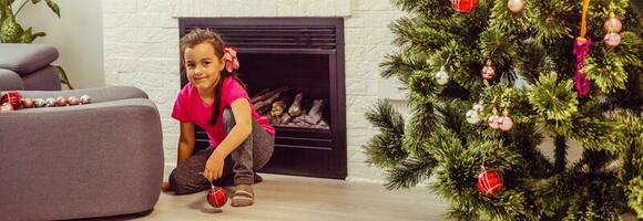 Child decorating Christmas tree Kid with Xmas gifts and toys. Little girl fireplace. Family with kids celebrate winter holidays. photo