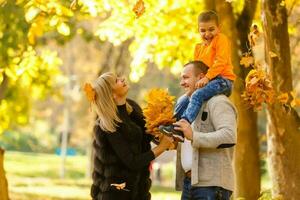 joven familia teniendo divertido en el otoño parque con su hijo. foto