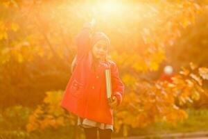 Pupil of primary school with book in hand. Girl with backpack near building outdoors. Beginning of lessons. First day of fall. photo