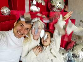 Christmas. Family. Technology. View on the smartphone. Dad, mom and daughter looking at camera and smiling while doing selfie photo