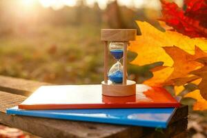 otoño hora tema, reloj de arena en caído hojas en varios colores con Copiar espacio. foto