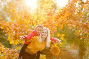 Mother giving daughter piggyback ride in autumn woodland photo