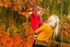 Young mother and her toddler girl have fun in autumn photo