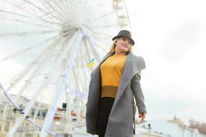 The young girl walks around the city near sights. Ferris wheel. Amusement park. autumn photo