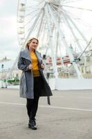 Young woman walking outdoors on the city street near ferris wheel smiling cheerful. photo