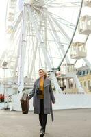 Young woman walking outdoors on the city street near ferris wheel smiling cheerful. photo