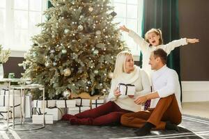 Family with gifts in front of Christmas tree photo