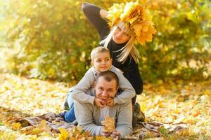 contento familia de Tres acostado en el césped en otoño. calentar efecto agregado. foto