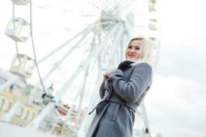 The young girl walks around the city near sights. Ferris wheel. Amusement park. autumn photo