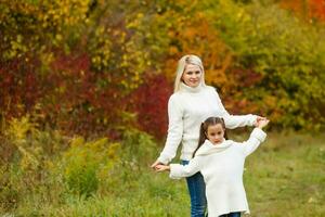 portrait of a young woman and her daughter in the autumn park photo