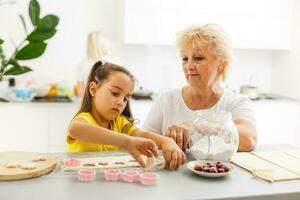 Cute little girl and her grandmother cooking on kitchen. photo