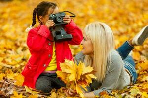 Young mother playing with her daughter in autumn park photo