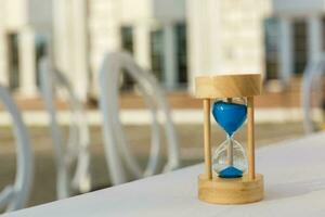 Sand running through the bulbs of an hourglass measuring the passing time in a countdown to a deadline, on a bright wooden background with copy space. photo