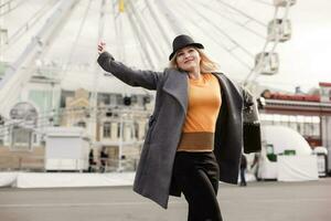 The young girl walks around the city near sights. Ferris wheel. Amusement park. autumn photo