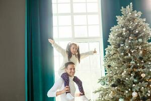 contento joven padre y su hija a hogar con Navidad árbol foto
