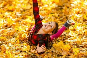 hermosa pequeño niña con otoño hojas al aire libre foto