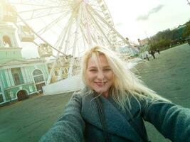 Young woman walking outdoors on the city street near ferris wheel smiling cheerful. photo