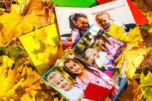 pequeño muchachas en un foto libro mentira en otoño hojas