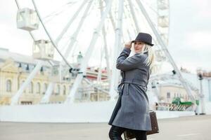 The young girl walks around the city near sights. Ferris wheel. Amusement park. autumn photo