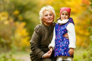 Grandmother and her granddaughter picking berries in the forest photo