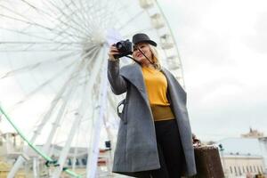 The young girl walks around the city near sights. Ferris wheel. Amusement park. autumn photo