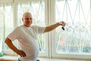 an old man holding a dead mouse photo