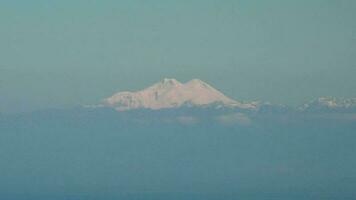 doppelt Gipfel Kegel geformt schneebedeckt Elbrus Berg Gipfel von lange Entfernung Zoomen video