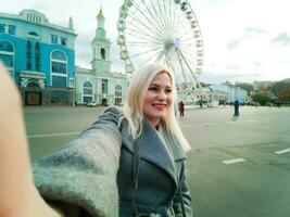 Young woman walking outdoors on the city street near ferris wheel smiling cheerful. photo