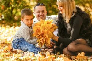 joven familia teniendo divertido en el otoño parque con su hijo. foto