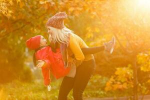 Mother giving daughter piggyback ride in autumn woodland photo