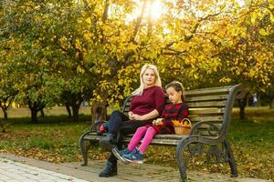 mother and daughter on a bench in autumn park photo