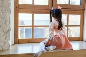 Adorable toddler girl looking at the window photo