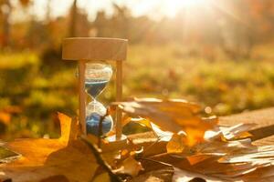 Autumn time theme, Sandglass on fallen leaves in various colors with copy space. photo